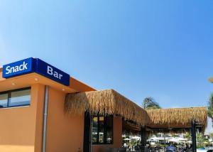 a snack bar with a straw roof at Atlantis Gardens in Mazotos