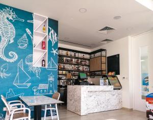 a restaurant with a blue wall with drawings on it at Atlantis Gardens in Mazotos