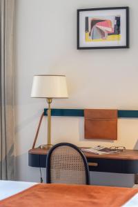 a desk with a lamp and a chair in a room at Hotel Le Friedland in Paris