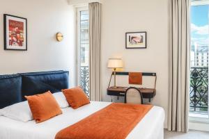 a bedroom with a bed and a desk and a window at Hotel Le Friedland in Paris