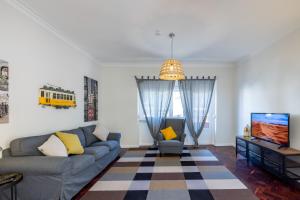 uma sala de estar com um sofá e uma televisão em Casa do Largo Electrico - Cozy and lovely apartment in the city center em Lisboa