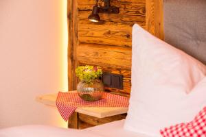 un jarrón de flores en una mesa junto a una cama en Gästehaus Fritz, en Mittelberg
