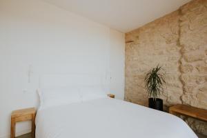 サン・ビセンテ・デ・ラ・ソンシエラにあるVT en San Vicente de la Sonsierraの白いベッドと石の壁が備わるベッドルーム1室