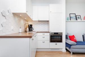 a kitchen with white cabinets and a blue couch at Marine Apartment 9B by Renters in Dziwnówek