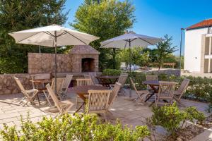 een patio met tafels, stoelen en parasols bij Villa Romana and Tea in Šilo