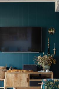 a living room with a flat screen tv on a blue wall at Boho Cottage in White Beach