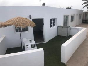 a white house with a grass umbrella on the side at Apartamentos Elena in Lajares +2 photos