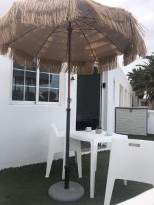 a table and chairs under a straw umbrella at Apartamentos Elena in Lajares