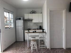 a kitchen with a white refrigerator and a table and stool at Apartamentos Elena in Lajares