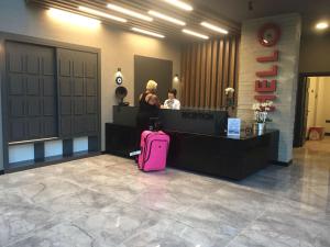 a woman standing at a counter with a pink suitcase at Ramira City Hotel - Adult Only (16+) in Alanya