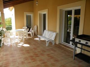 a porch with a bench and a table and chairs at Maison tout confort avec piscine à Bedarrides in Bédarrides