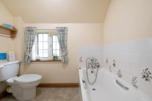 a bathroom with a toilet and a tub and a sink at Marris Cottage in Grimsby +6 photos