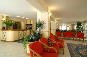 een wachtkamer met rode stoelen en planten bij Hotel Casali in Cervia