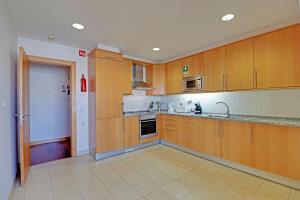 a kitchen with wooden cabinets and a sink at Albufeira Modern with pool by Homing in Albufeira