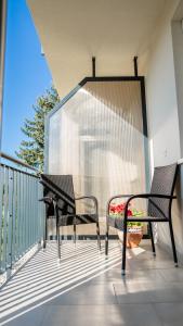 2 Stühle und ein Tisch auf dem Balkon in der Unterkunft Főnix Apartman in Lenti