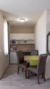Főnix Apartman في لينتي: مطبخ وغرفة طعام مع طاولة وكراسي