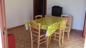a dining room table with chairs and a television at Residenza I Gabbiani Valledoria in Valledoria