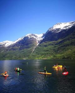 un grupo de personas en kayaks en un lago con montañas en Oldevatn Camping, en Olden