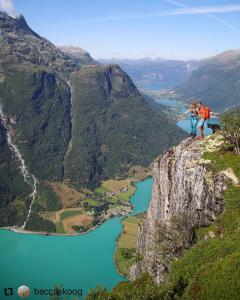 twee mensen aan de rand van een berg met uitzicht op een rivier bij Oldevatn Camping in Olden