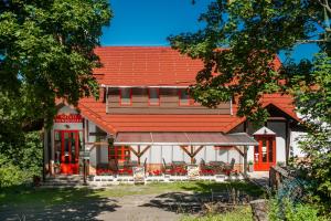 ein Haus mit einem orangenen Dach mit Stühlen davor in der Unterkunft Natali Vendégház és étterem Mátra in Matraszentlaszlo