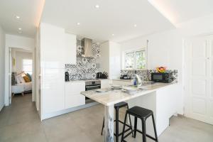 a kitchen with white cabinets and a counter with stools at Waterside Village - Sea View Apartment in Alagoas +10 photos
