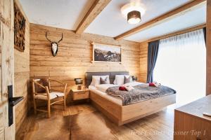 Schlafzimmer mit Holzwänden, einem Bett und einem Stuhl in der Unterkunft Chalet Leßner in Leutasch