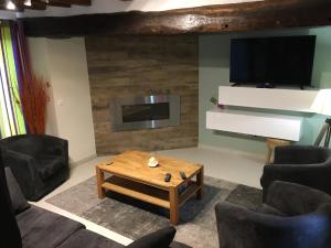 ein Wohnzimmer mit einem TV und einem Couchtisch in der Unterkunft Le COLVERT in Le Hanouard
