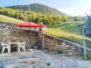 a stone wall with a table and a red umbrella at La Meisoun de Lanta - cir n 0003 in Introd