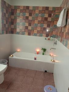 a bathroom with a tub with candles and a toilet at Rudram Hotel Yoga & Ayurveda Retreat in Rishīkesh