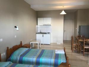 a bedroom with a bed and a kitchen with a table at Marinos Studios in Póros Kefalonias