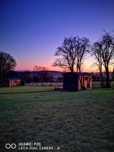 a shed in a field with a sunset in the background at the cwch in Llanbister