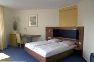 a bedroom with a bed and a desk and a table at Hotel Kurpfalz in Speyer