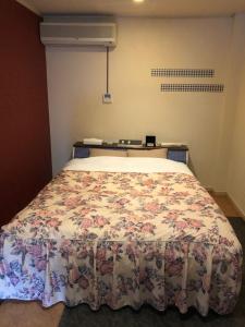 1 dormitorio con 1 cama con colcha de flores en Hotel Mariage Tsukuba, en Tsukuba