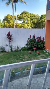 a garden with red flowers and a white fence at Casa em Ponta De Pedras- Encanto do Litoral! in Recife