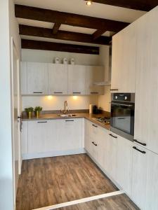 a kitchen with white cabinets and a wooden floor at Torenkamer Middelburgh in Middelburg