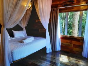 1 dormitorio con 1 cama con cortinas y ventana en Utan Teluk Nipah, en Pangkor