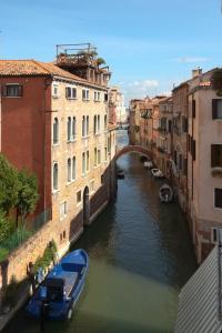 ein Kanal zwischen zwei Gebäuden mit einem Boot im Wasser in der Unterkunft Corte dei Miracoli in Venedig
