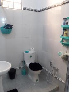 a bathroom with a toilet with a black seat and a sink at Joli Chalet plain-pied avec jardin privatif in Tlemcen