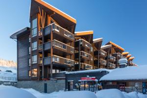a building in the snow with a bus in front of it at Ridderleiligheter in Beitostøl