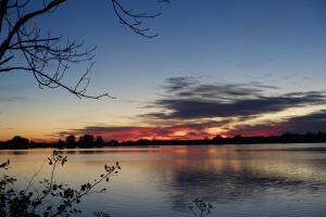 a view of a lake with a sunset in the background at De lütte im gulen Hus in Kappeln