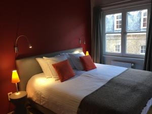 a bedroom with a bed with red walls and two windows at B&B Setola in Bruges
