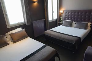 a hotel room with two beds and two windows at Hôtel Saint-Charles in Paris
