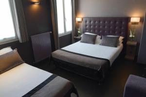 a hotel room with two beds and two windows at Hôtel Saint-Charles in Paris