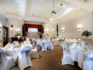 チェスターにあるマクドナルド ニュー ブロッサムズ ホテルの白いテーブルと椅子が備わる宴会場