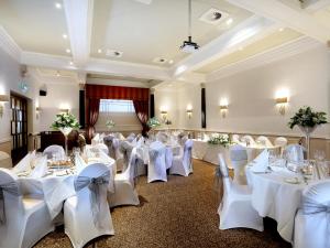 um salão de banquetes com mesas e cadeiras brancas em Macdonald New Blossoms Hotel em Chester