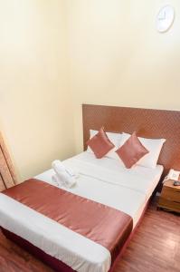 Al Karnak Hotel في دبي: غرفة نوم بسرير كبير مع وسائد بنية وبيضاء