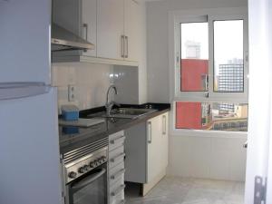 a kitchen with a sink and a stove and windows at Apartamentos Les Dunes Centro in Benidorm