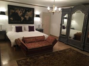 een slaapkamer met een bed, een stoel en een spiegel bij Le Belvédère in Thiviers