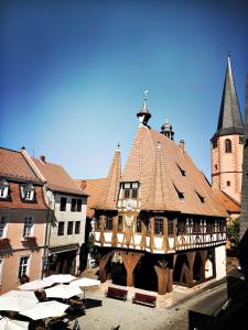 a building with a clock tower and a building with umbrellas at Schwarzer Adler in Michelstadt