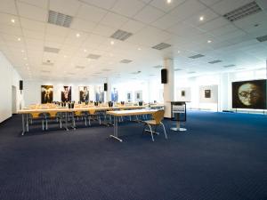 Großes Zimmer mit Tischen, Stühlen und Gemälden in der Unterkunft bonjour Tagungshotel Stuttgart-Gerlingen in Gerlingen